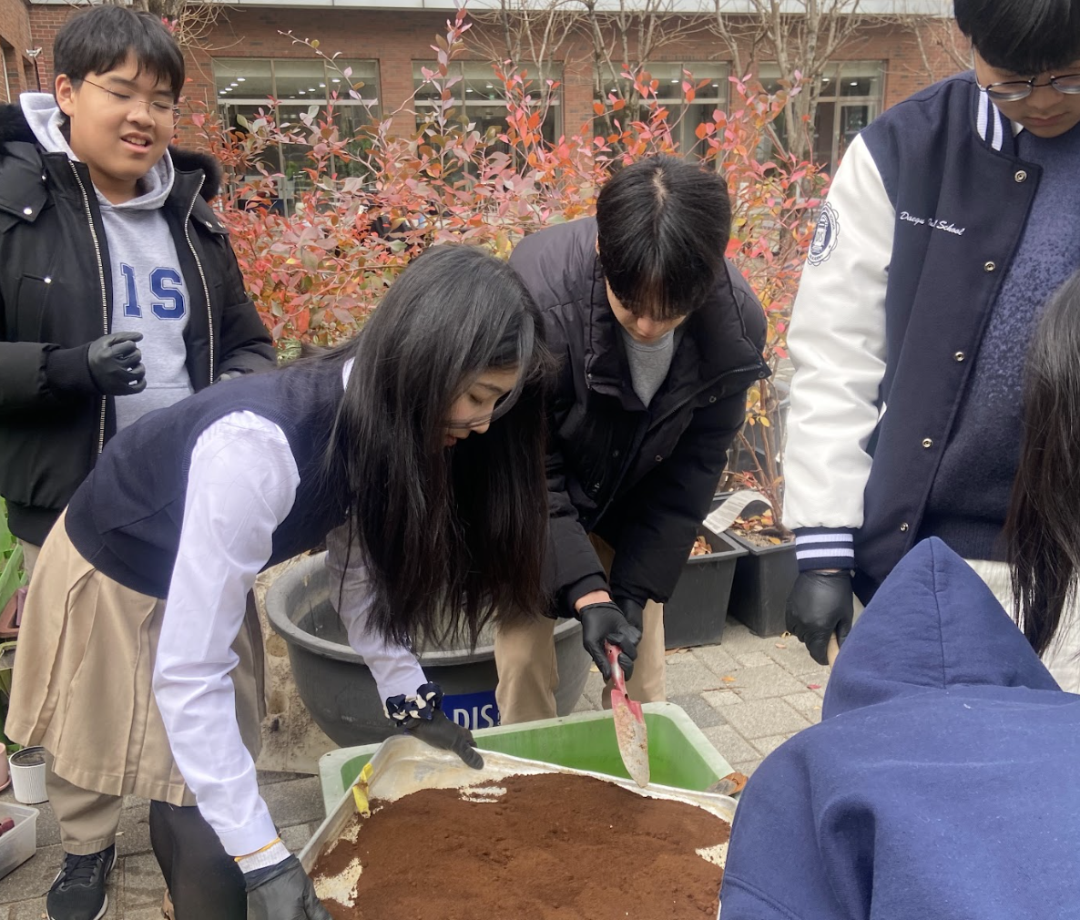Members mixing grounds with sesame cake into compost
